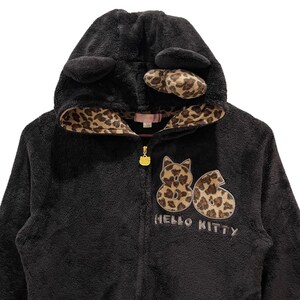 Peut inclure: Sweat-shirt &agrave; capuche noir en polaire avec une doublure &agrave; imprim&eacute; l&eacute;opard et un motif Hello Kitty. La capuche est orn&eacute;e d'oreilles de chat noires et d'une bordure &agrave; imprim&eacute; l&eacute;opard.