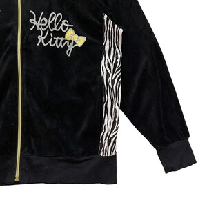 May include: Black velour zip-up jacket with a zebra print stripe down the side and "Hello Kitty" embroidered on the front.
