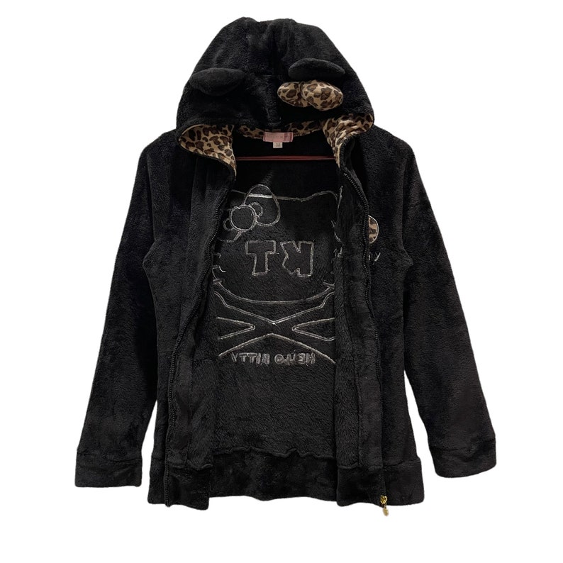 Peut inclure: Sweat-shirt &agrave; capuche noir en polaire avec un motif Hello Kitty et une doublure en imprim&eacute; l&eacute;opard. La capuche est orn&eacute;e d'oreilles de chat.