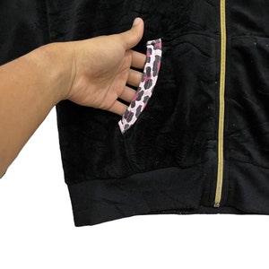 Pode incluir: Casaco preto de veludo com z&iacute;per e um detalhe de bolso com estampa de leopardo rosa e preto.
