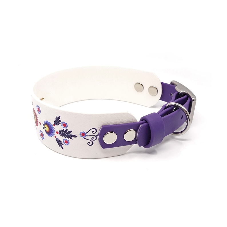 Puede incluir: Collar de perro blanco con una correa morada y un dise&ntilde;o floral. El collar tiene herrajes met&aacute;licos plateados.