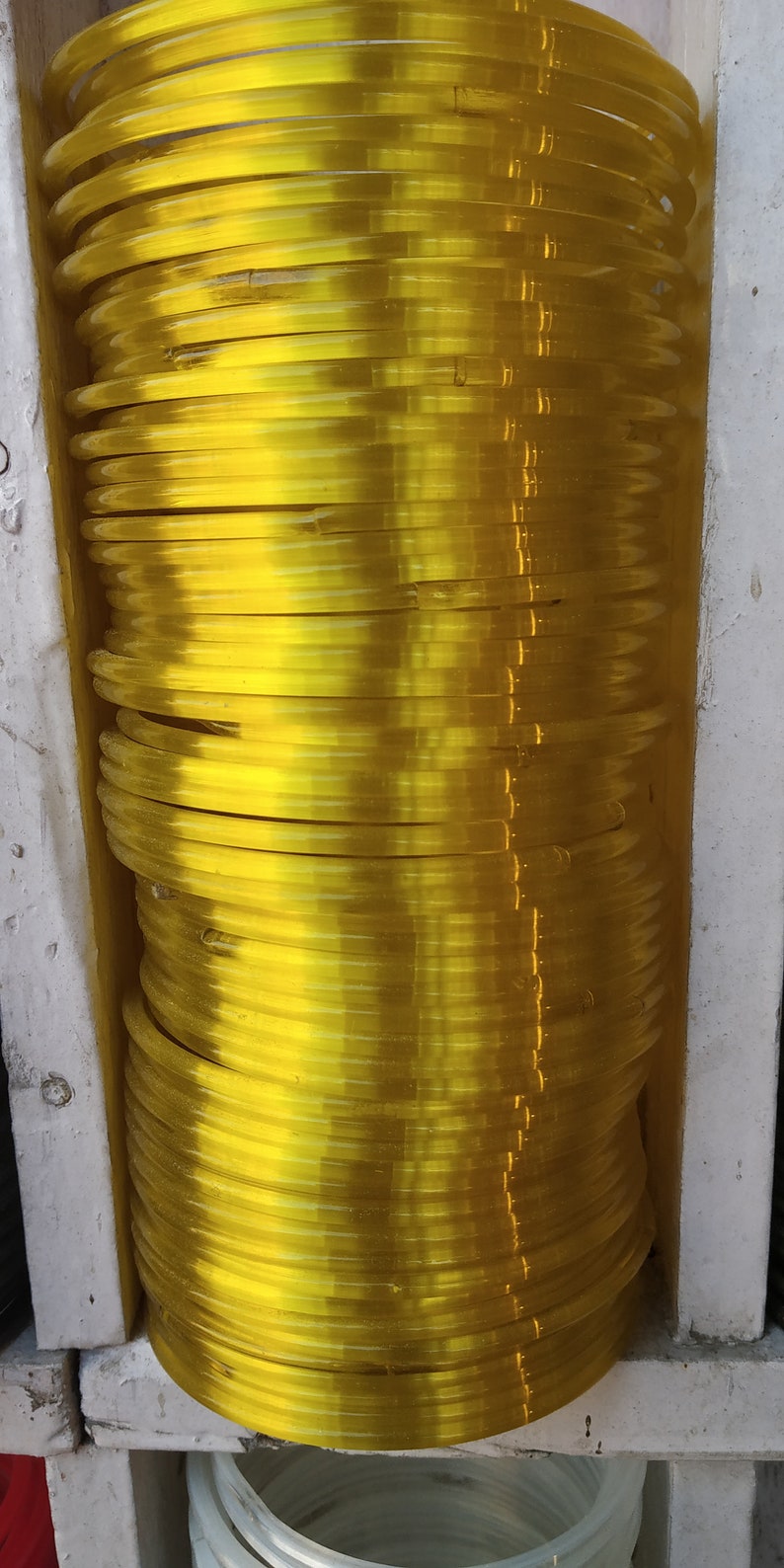 May include: A stack of yellow plastic bangles. The bangles are stacked on top of each other and are arranged in a circular pattern.