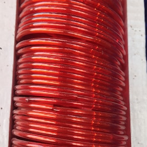 May include: A stack of red plastic bangles. The bangles are stacked on top of each other and are arranged in a circular pattern.