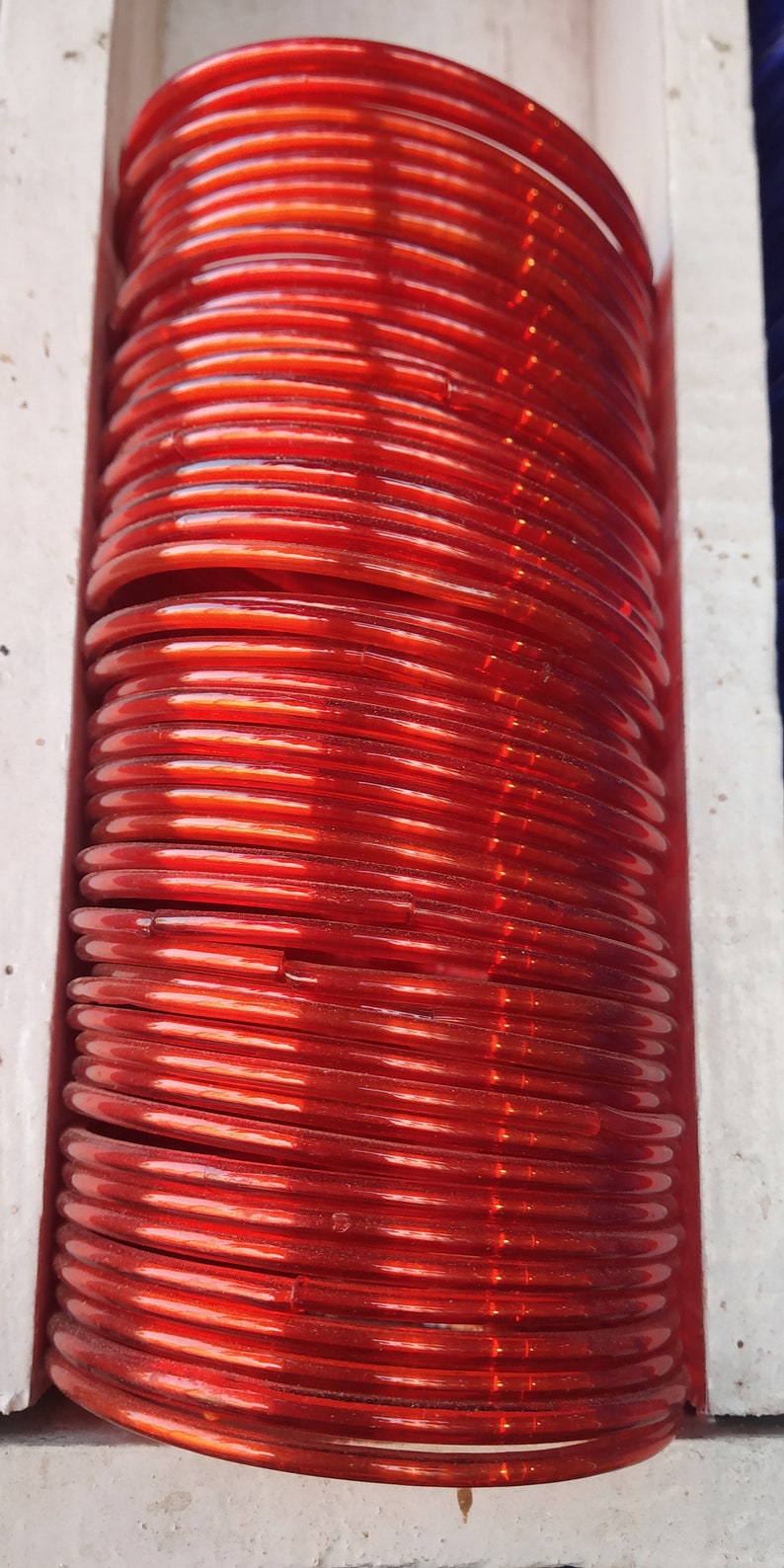 May include: A stack of red plastic bangles. The bangles are stacked on top of each other and are arranged in a circular pattern.