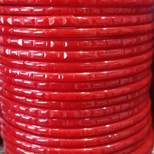 Puede incluir: Una pila de brazaletes de pl&aacute;stico rojo con un dise&ntilde;o texturizado. Los brazaletes est&aacute;n apilados uno encima del otro y todos son del mismo tama&ntilde;o.