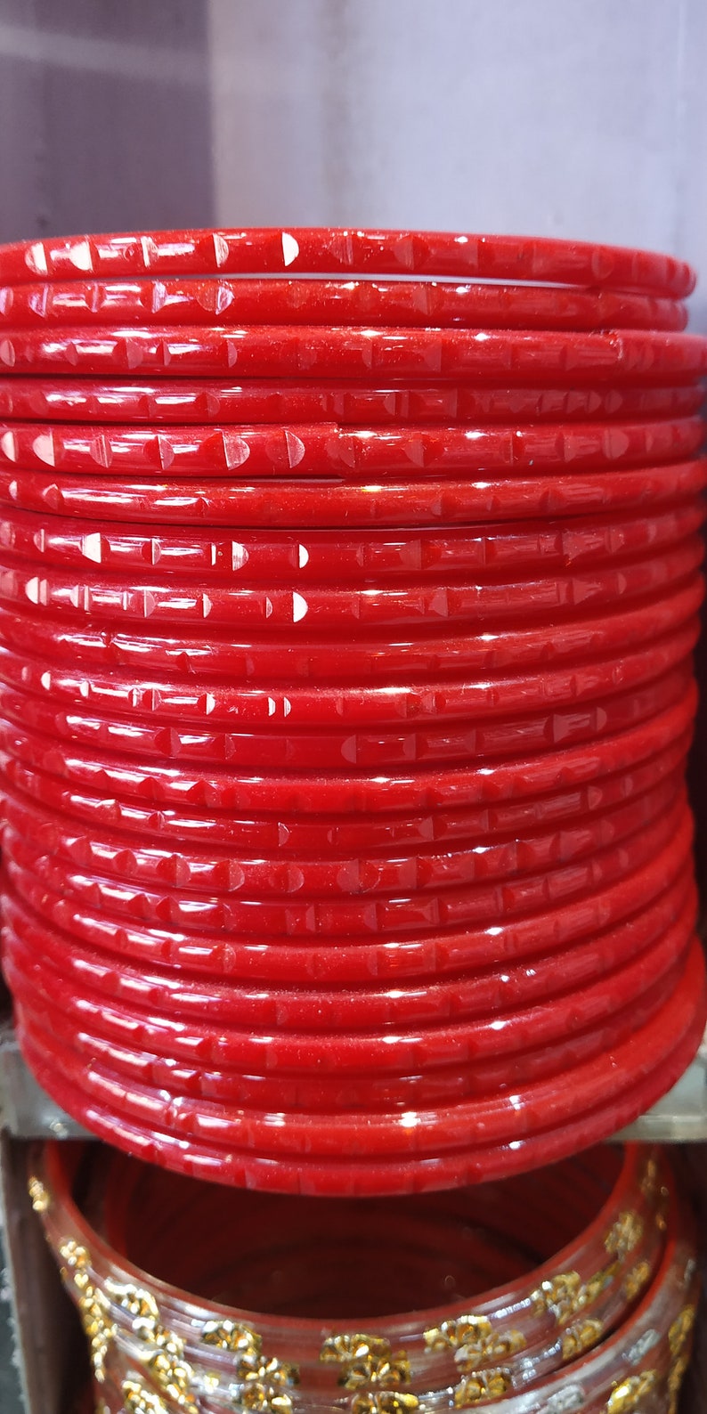 Puede incluir: Una pila de brazaletes de pl&aacute;stico rojo con un dise&ntilde;o texturizado. Los brazaletes est&aacute;n apilados uno encima del otro y todos son del mismo tama&ntilde;o.