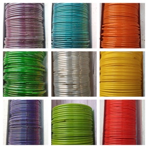 Puede incluir: Una colección de pulseras coloridas apiladas en filas. Las pulseras son de vidrio y vienen en una variedad de colores, incluyendo morado, verde, azul, plateado, amarillo y rojo.