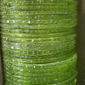 Puede incluir: Una pila de brazaletes de vidrio verde con un dise&ntilde;o texturizado. Los brazaletes est&aacute;n apilados uno encima del otro y est&aacute;n dispuestos en un patr&oacute;n circular.