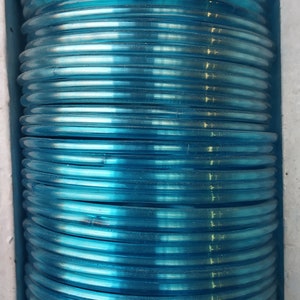 May include: A stack of light blue plastic bangles. The bangles are stacked on top of each other and are arranged in a circular pattern.