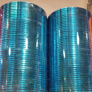 May include: A stack of blue glass bangles, wrapped in plastic, with a shiny, reflective surface.