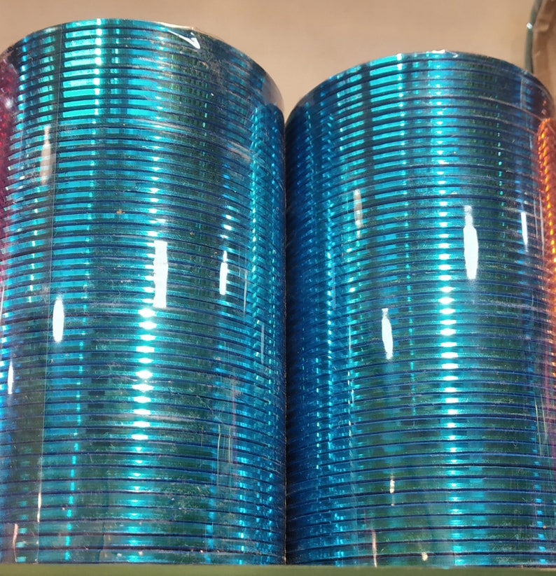 May include: A stack of blue glass bangles, wrapped in plastic, with a shiny, reflective surface.