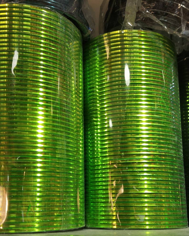 May include: A stack of shiny green bangles, wrapped in plastic, ready for sale.