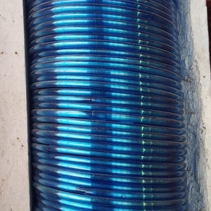 May include: A stack of blue glass bangles. The bangles are stacked on top of each other and are arranged in a vertical column.