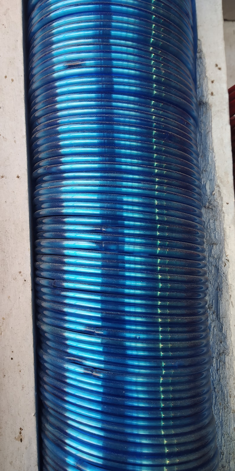 May include: A stack of blue glass bangles. The bangles are stacked on top of each other and are arranged in a vertical column.