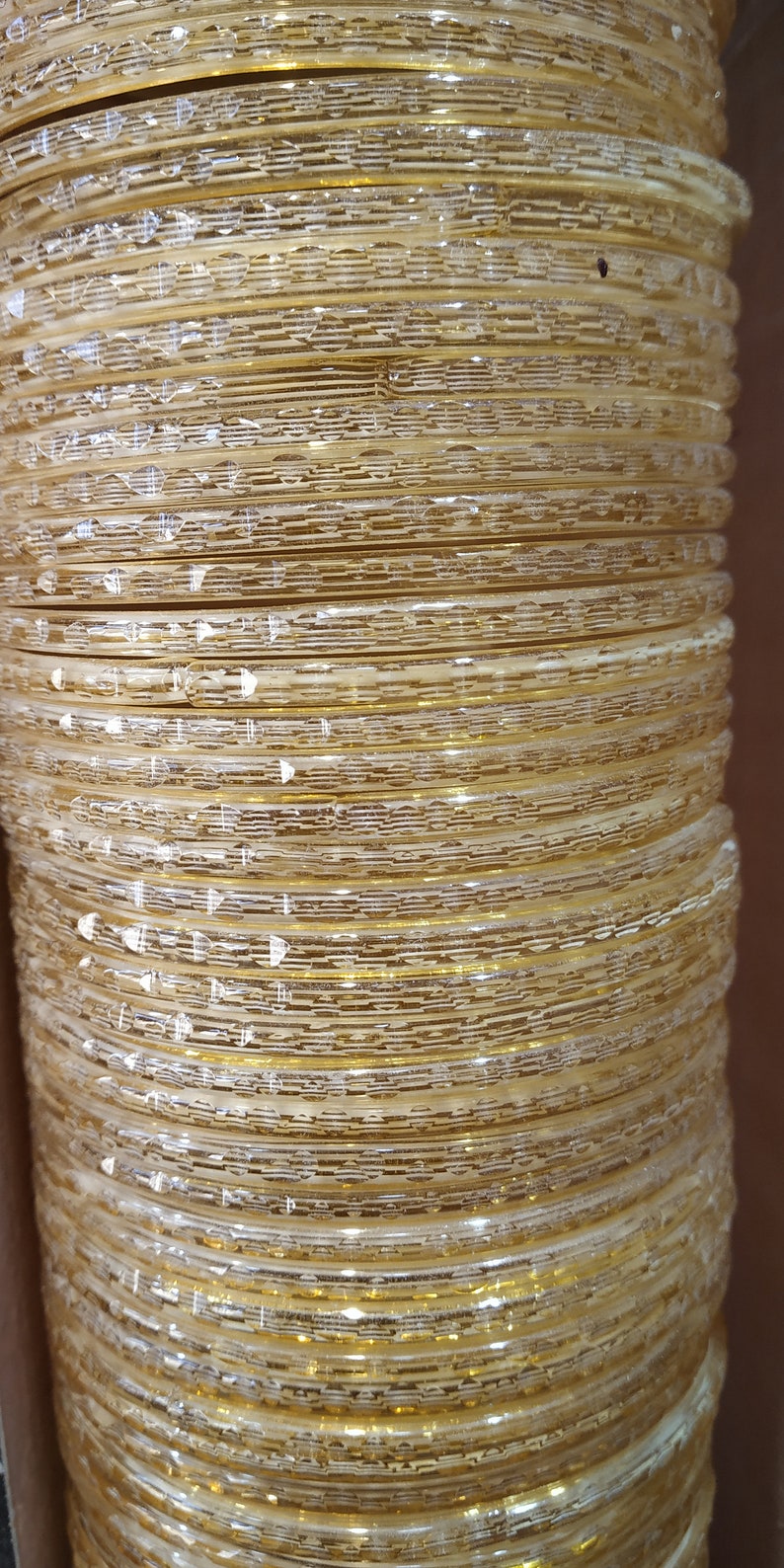 Puede incluir: Una pila de brazaletes de color dorado con un dise&ntilde;o texturizado. Los brazaletes est&aacute;n apilados uno encima del otro, creando un patr&oacute;n visual.