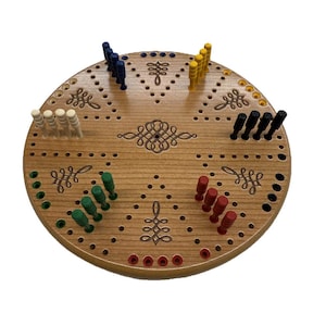 May include: A wooden cribbage board with a circular design. The board has six different colored pegs, including red, blue, green, yellow, black, and white.