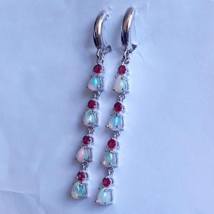 May include: A pair of silver dangle earrings with a cascade of white opal and red gemstone drops.