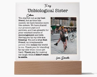 Puede incluir: Una placa de acrílico blanco con una base de madera presenta una foto de dos mujeres sonriendo y un mensaje sincero sobre la amistad. El texto dice: "A mi hermana no biológica Colleen Empezaste como mi mejor amiga, pero con el tiempo nos hemos convertido en algo más que hermanas. Hemos compartido nuestras mayores alegrías y penas, y estoy agradecida por tu constante fuente de aliento y amor. Tenerte a mi lado es una bendición. Eres una verdadera mejor amiga, una persona irremplazable que significa el mundo para mí. Gracias por estar ahí para mí cuando las cosas se ponen difíciles. Gracias por hacerme reír cuando no quería. Con cariño, Danielle"