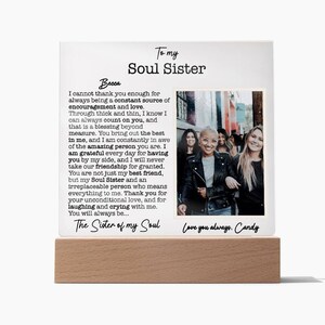 May include: A white framed photo with a wood base, featuring a group of friends smiling and posing for a photo. The photo is accompanied by a heartfelt message to a friend, calling them a "Soul Sister" and expressing gratitude for their friendship. The message reads, "I cannot thank you enough for always being a constant source of encouragement and love. Through thick and thin, I know I can always count on you, and that is a blessing beyond measure. You bring out the best in me, and I am constantly in awe of the amazing person you are. I am grateful every day for having you by my side, and I will never take our friendship for granted. You are not just my best friend, but my Soul Sister and an irreplaceable person who means everything to me. Thank you for your unconditional love, and for laughing and crying with me. You will always be... The Sister of my Soul. Love you always. Candy."