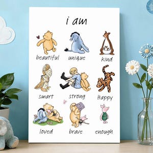May include: A white canvas print with the words "i am" above illustrations of Winnie the Pooh characters, each labeled with a positive adjective. The background is light blue with decorative clouds and a moon.