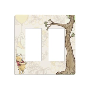 May include: A decorative light switch cover featuring Winnie the Pooh. The cover has two openings and is decorated with a tree, a balloon, and a cartoon image of Winnie the Pooh. The background has a floral and honeycomb pattern.