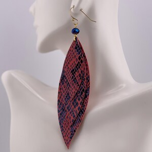 Peut inclure: Une paire de longues boucles d'oreilles superpos&eacute;es avec un motif peau de serpent rouge et bleu marine. Les boucles d'oreilles sont suspendues &agrave; des crochets dor&eacute;s et comportent une petite perle bleu fonc&eacute; en haut.