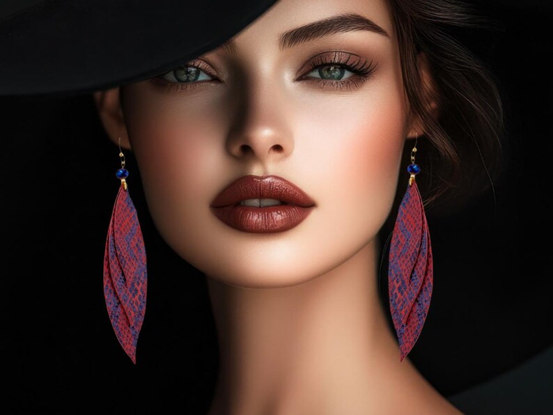 Peut inclure: Portrait d'une personne portant des boucles d'oreilles en forme de plumes, &agrave; motifs de peau de serpent rouge et violet, avec des accents bleus. La personne a les cheveux fonc&eacute;s, un chapeau noir et du rouge &agrave; l&egrave;vres fonc&eacute;.