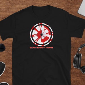 Peut inclure: T-shirt noir avec un graphique circulaire rouge et blanc et le texte "Dare Mighty Things".