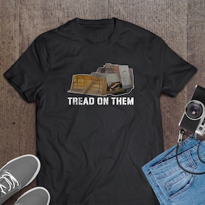 May include: Black t-shirt with a graphic of a yellow bulldozer with the text "Tread on Them" in white.