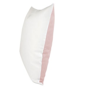 May include: A white pillow with a pink border. The pillow is made of a soft, comfortable material and is perfect for adding a touch of color to any room.