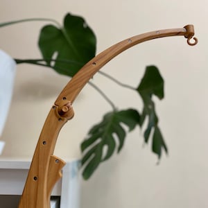 May include: A wooden mobile arm with a clamp for attaching to a crib or other surface. The arm is curved and has a hook at the end for hanging mobile toys.