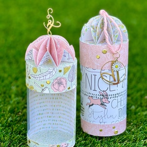 Puede incluir: Dos cajas de regalo de papel rosa y blanco con papel decorativo y detalles dorados. Las cajas están decoradas con patrones florales, lunares y las palabras "Nice", "Cheery", "Stylin'" y "Do Good".