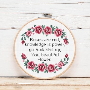 May include: A white embroidery hoop with a red and green floral design. The hoop contains the text "Roses are red, knowledge is power, go fuck shit up, You beautiful flower."