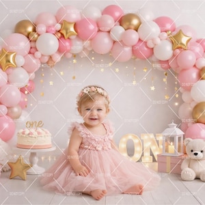 Puede incluir: Una escena festiva de primer cumpleaños con un arco de globos rosas y dorados, una tarta y un bebé con un vestido rosa. Decoraciones de estrellas doradas y un oso de peluche completan el ambiente festivo. Se muestra la palabra "one".