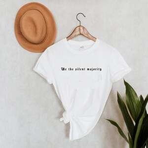 Könnte beinhalten: Weißes T-Shirt mit dem Aufdruck "We the silent majority" in Schwarz auf der Vorderseite.