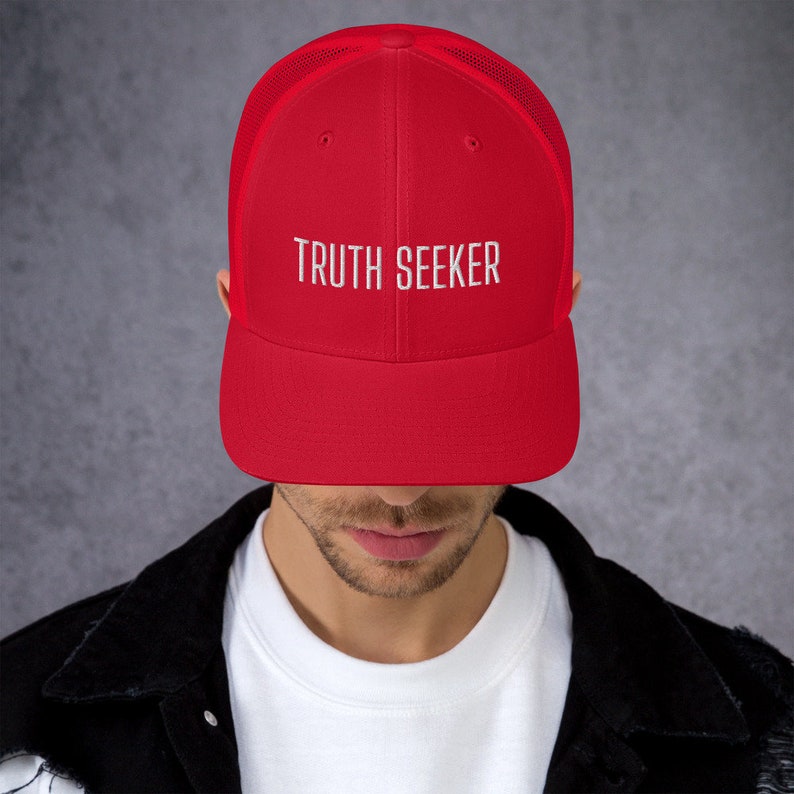 May include: A red and black mesh trucker hat with the text "TRUTH SEEKER" embroidered in white on the front.