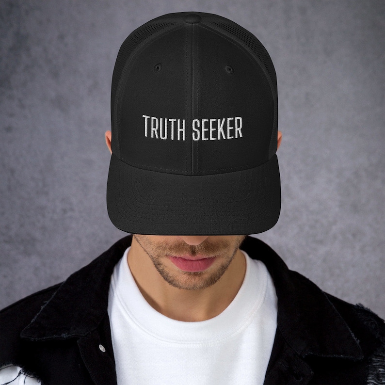 May include: A black mesh trucker hat with a white embroidered design that says "TRUTH SEEKER".