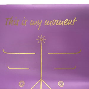 May include: Purple yoga mat with gold lettering that says "This is my moment" and gold geometric designs.