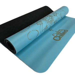 May include: A blue yoga mat with a gold floral design and the text "Calm & Chilled" printed on it. The mat is rolled up and the black underside is visible.