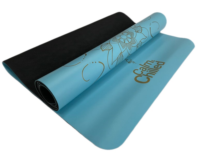 May include: A blue yoga mat with a gold floral design and the text "Calm & Chilled" printed on it. The mat is rolled up and the black underside is visible.