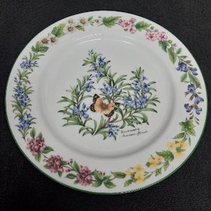 May include: A white ceramic plate with a green rim features a floral design with a butterfly and the text "Rosemary, Autumn Branch".