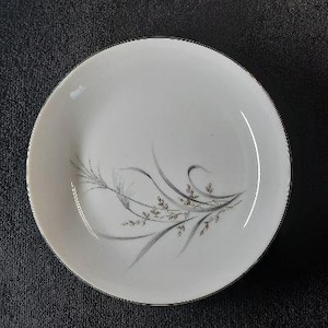 May include: A white ceramic bowl with a delicate gray and gold floral design. The bowl has a simple, elegant design and is perfect for serving a variety of dishes.