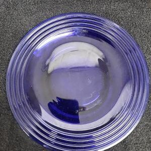 May include: A blue glass plate with a concentric circle design. The plate is empty and has a slight sheen.