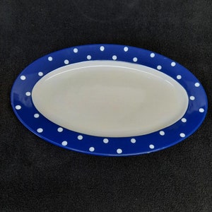 May include: A white oval serving platter with a blue rim and white polka dots.