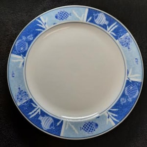 May include: A white ceramic plate with a blue and white fish design. The plate has a light blue background with white fish and seaweed designs.
