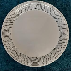 May include: A white ceramic dinner plate with a black concentric circle design.