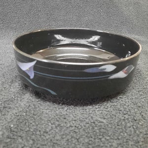 May include: A black ceramic bowl with a blue and white floral design. The bowl is round and has a smooth, glossy finish.