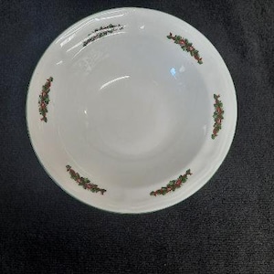 May include: A white ceramic bowl with a green and red holly design. The bowl is perfect for serving soup, cereal, or salad.