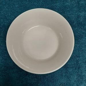 May include: A white ceramic bowl with a smooth, rounded rim. The bowl is empty and has a slight sheen.