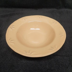 May include: A pale yellow ceramic bowl with a scalloped rim and a decorative design of stylized leaves around the edge.